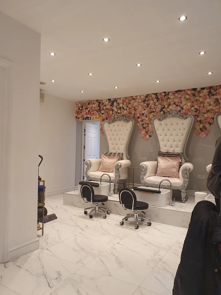 The salon's marble-floored room with two ornate white chairs against a floral wall