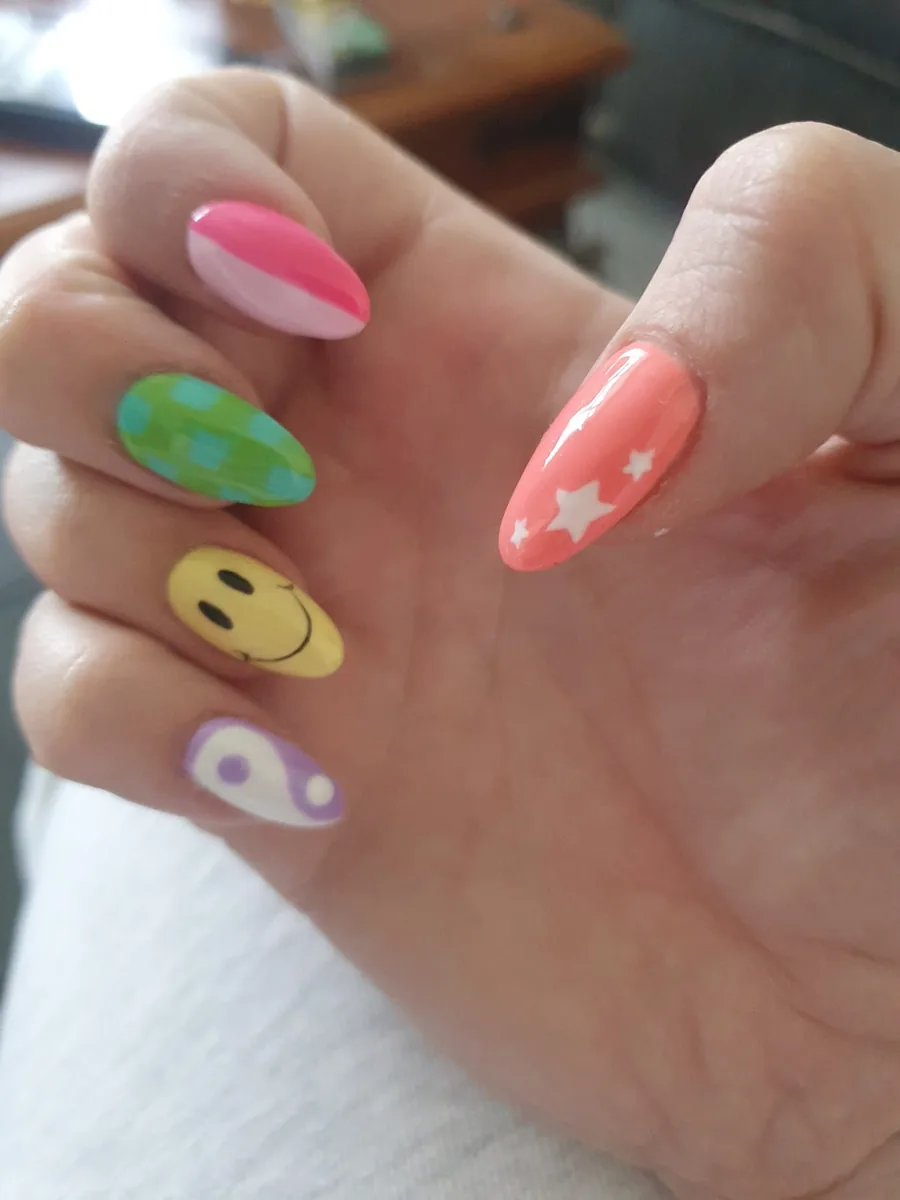 Long almond nails with bright novelty art including a smiley face and a star
