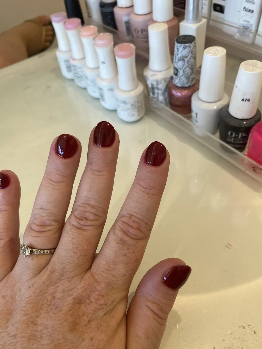 A nail technician painting a client's nails at a salon table