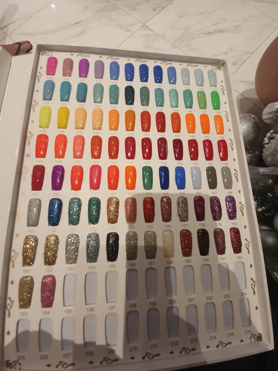 An open display case of nail colour sample tips laid out in rainbow rows